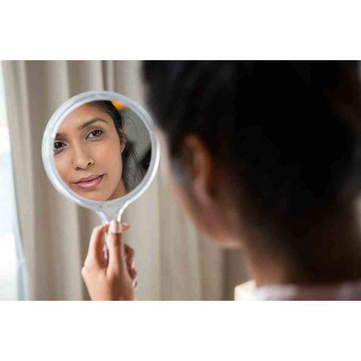woman looking at skin in mirror